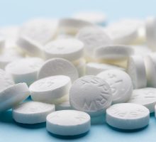 benefits and risks of aspirin tablets on blue paper